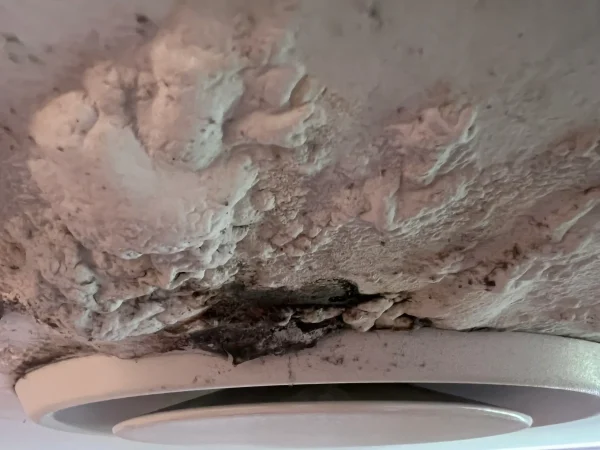 Dark staining and peeling ceiling coating around a round air vent