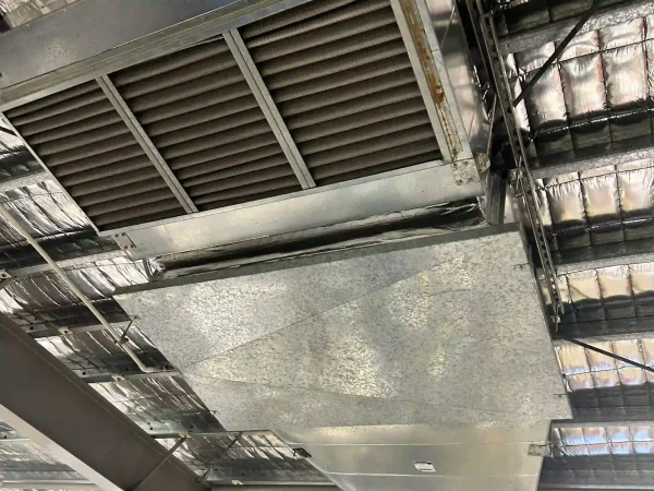 Metal ventilation ductwork beneath an insulated roof