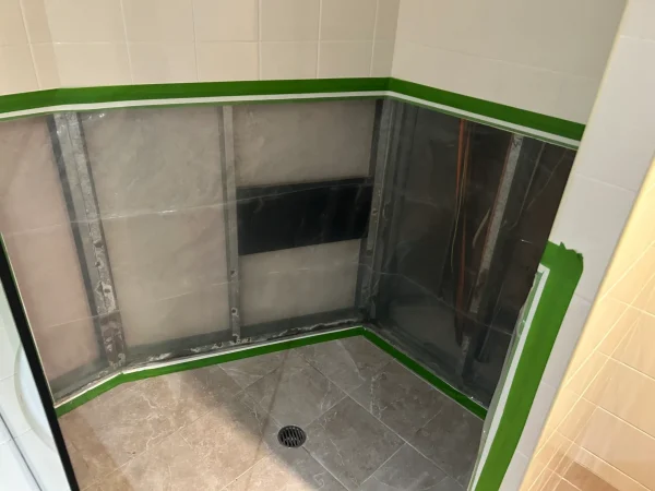 Shower enclosure with wall linings removed and tiled floor exposed